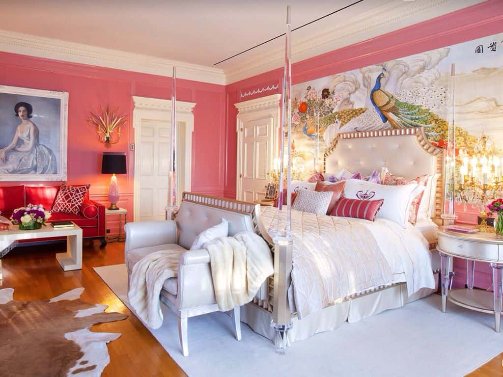 华丽的主卧室，粉红色的壁板墙壁上装饰着可爱的肖像和一幅大型艺术品，为玻璃四柱床设置了奇妙的背景。