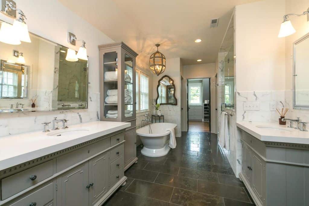 乡村风格的主浴室，带有独立浴缸，两个下置水槽和瓷砖地板。