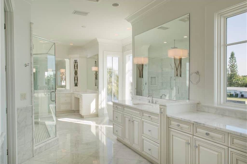 传统的白色主浴室，带有壁灯和凸起的面板柜。
