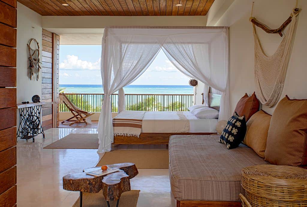 中型岛屿风格的主卧室，放松的色调来自波西米亚家具，白色墙壁和瓷砖地板。