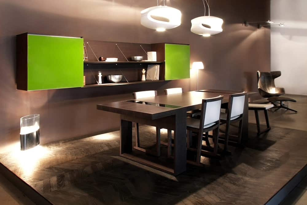 这是一个现代化的餐厅，有黑色的墙壁，平台地板和黑色的木桌，由现代的白色吊灯照明。