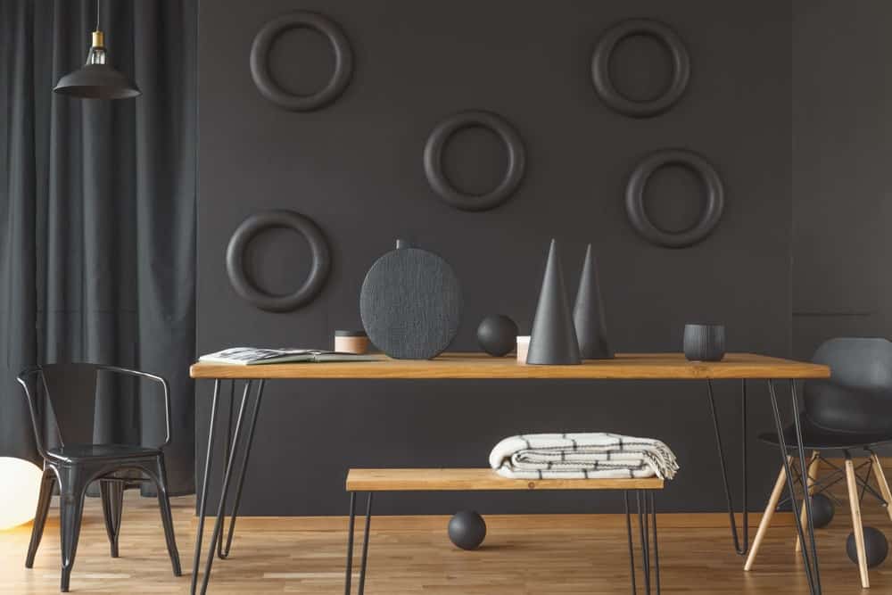 明亮的漆黑的墙壁与黑色的装饰强调，使木桌脱颖而出。它具有与硬木地板相同的色调，以获得良好的平行度。