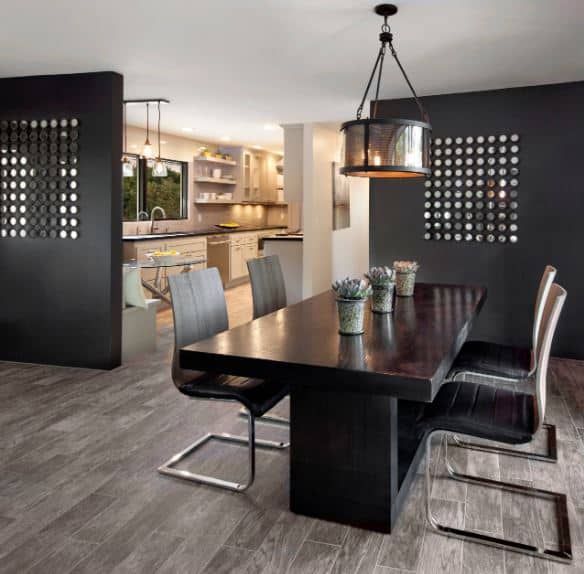 黑色的现代餐桌搭配现代的黑色皮革餐椅，与带有装饰孔的黑色面板相匹配，作为餐厅和家庭其他部分的分隔。