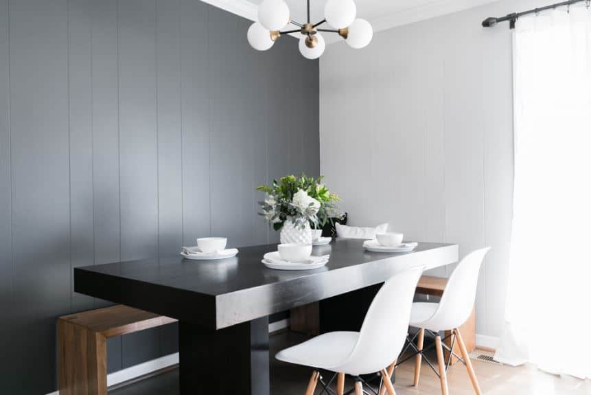 漆黑的木质餐桌与l形木凳后面的黑色墙壁相得益彰。