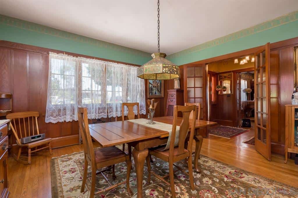 上面的墙壁是绿色的色调，与白色的天花板和木制的墙壁形成良好的中介，与硬木地板相匹配。地板上铺着绿色花卉图案的区域地毯，与木桌和小提琴背椅形成对比。