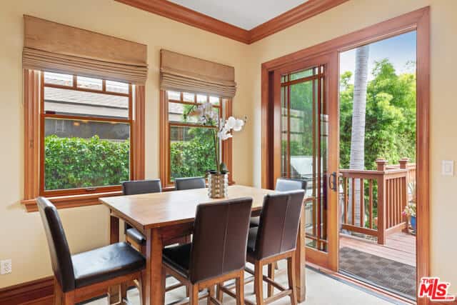 帕森斯真皮椅子环绕着木质餐厅，与窗户的框架和通往户外的玻璃推拉门很好地搭配在一起。这为这个私密的用餐区提供了空间感，硬木地板上的白色地毯进一步增强了空间感。