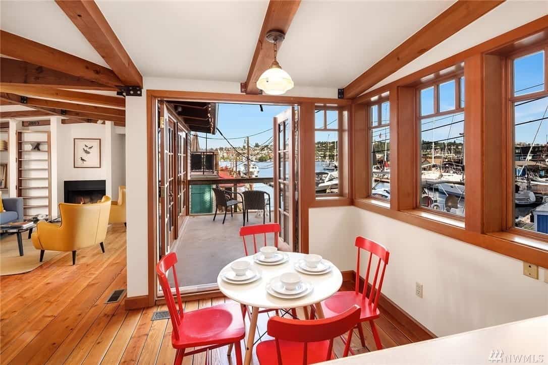 这个非正式的餐厅有木制的板条靠背椅子，带有戏剧性的红色色调，与白色的小圆桌和白墙形成矛盾。天花板上有裸露的木梁，与硬木地板、围绕用餐区的窗户和玻璃门的框架形成映衬。