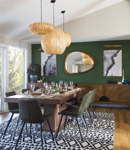 这个餐厅的绿色墙壁是一个很好的背景，独特的艺术品和吊灯在木桌上，周围是配套的绿色椅子。