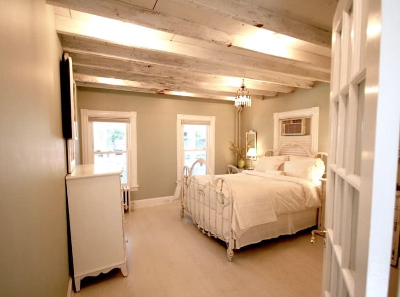 主卧室地毯地板和天花板与暴露梁。房间里有一个漂亮的床集。