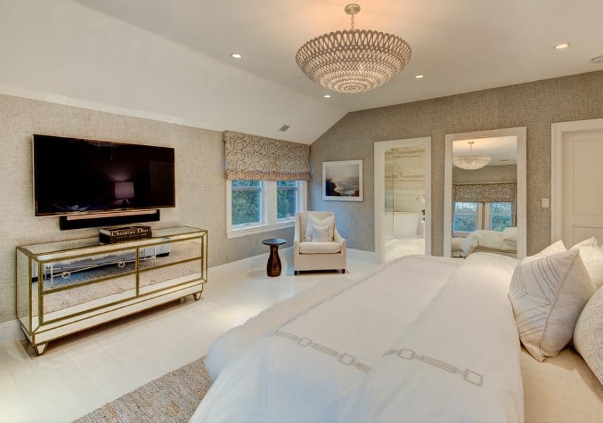 宽敞的主卧室配有舒适的床和宽屏电视机，周围环绕着设计优雅的墙壁，并由华丽的顶灯照明。