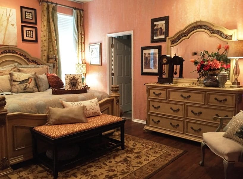 主卧室与橙色的墙壁和硬木地板,一个棕色的小地毯大床集坐落的地方。