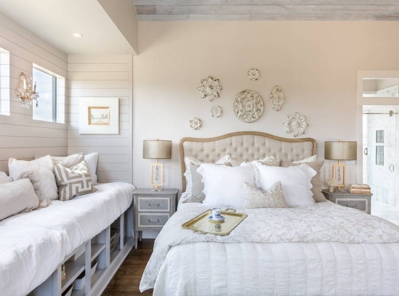 破旧别致的主卧室有一个优雅的床上设置点优雅的台灯在匹配的床头柜上。墙上也提供了华丽的墙来。