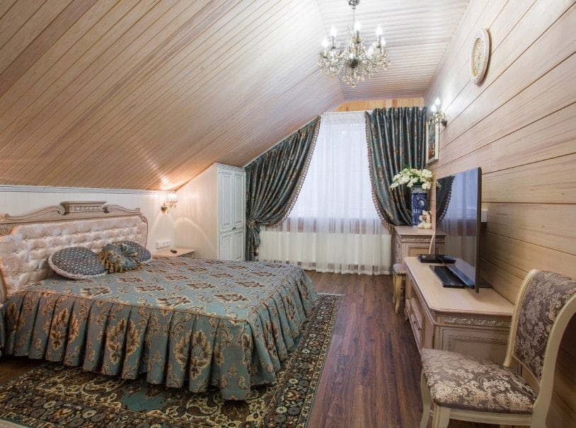 主卧室设有定制的木质天花板和硬木地板，以及木墙。它有一个华丽的床，前面有一个大平板电视。