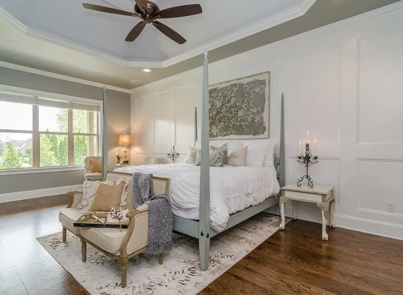 一个宽敞的主卧室有一个惊人的托盘天花板和硬木地板。它有一个漂亮的灰色的床集时尚面积地毯下面。