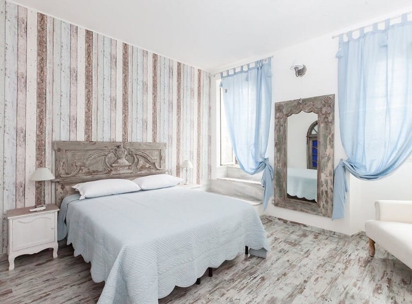 主卧室有时尚的木墙和硬木地板。它有一张漂亮的双人床和薄薄的蓝色窗帘。