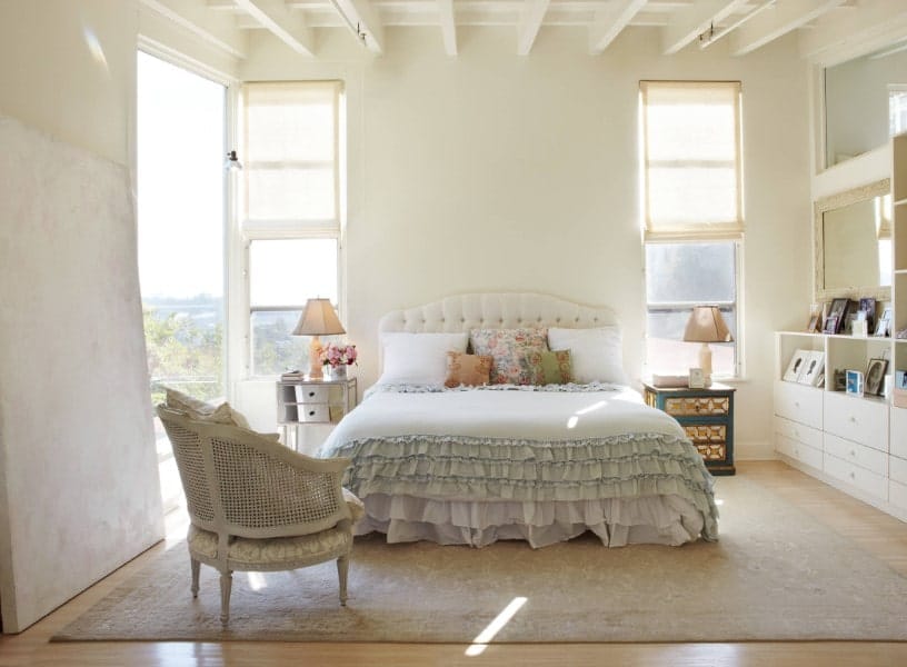 破旧别致的主卧室里有白色的墙,白色的天花板的栋梁。它也有一个可爱的床上设置一块地毯覆盖了实木地板。