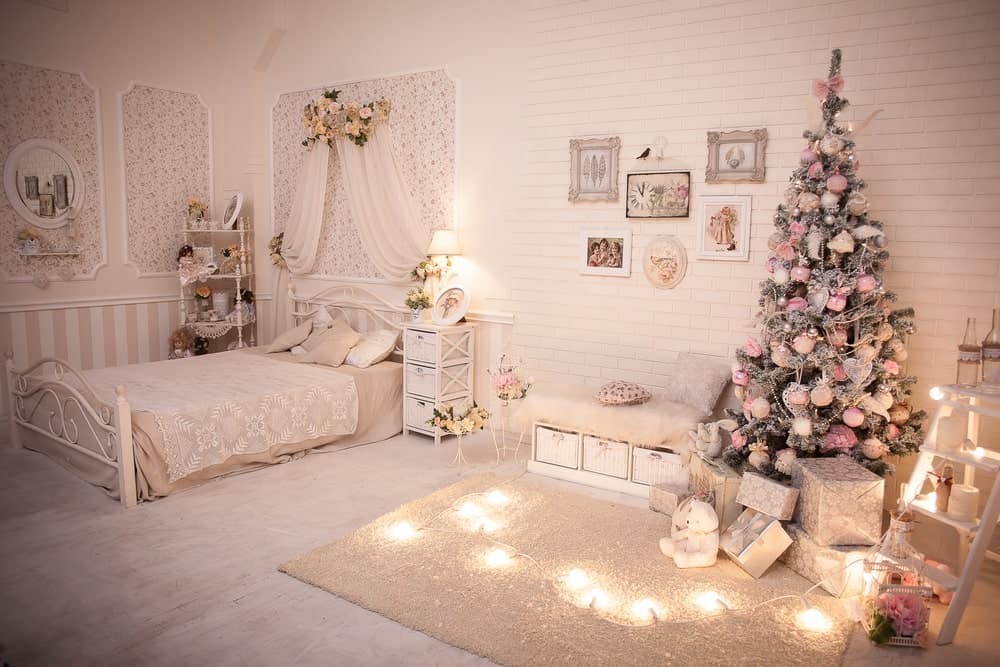 一个破旧别致的主卧室，有可爱的床设置和优雅的墙壁装饰，以及地毯地板。房间还拥有一个华丽的圣诞树装饰的侧面。