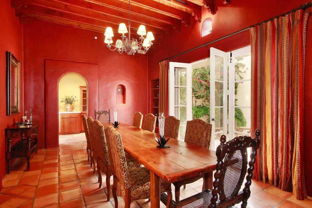 地中海红色餐厅，配有长方形木桌和枝形吊灯。