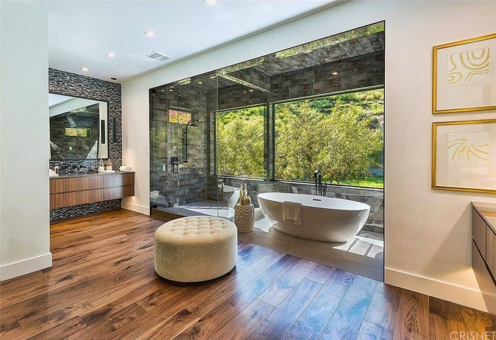 大型主要浴室，带有硬木地板。窗户附近有一个独立的浴缸，俯瞰着酒店美丽的花园区域。角落里也有一个步入式淋浴。