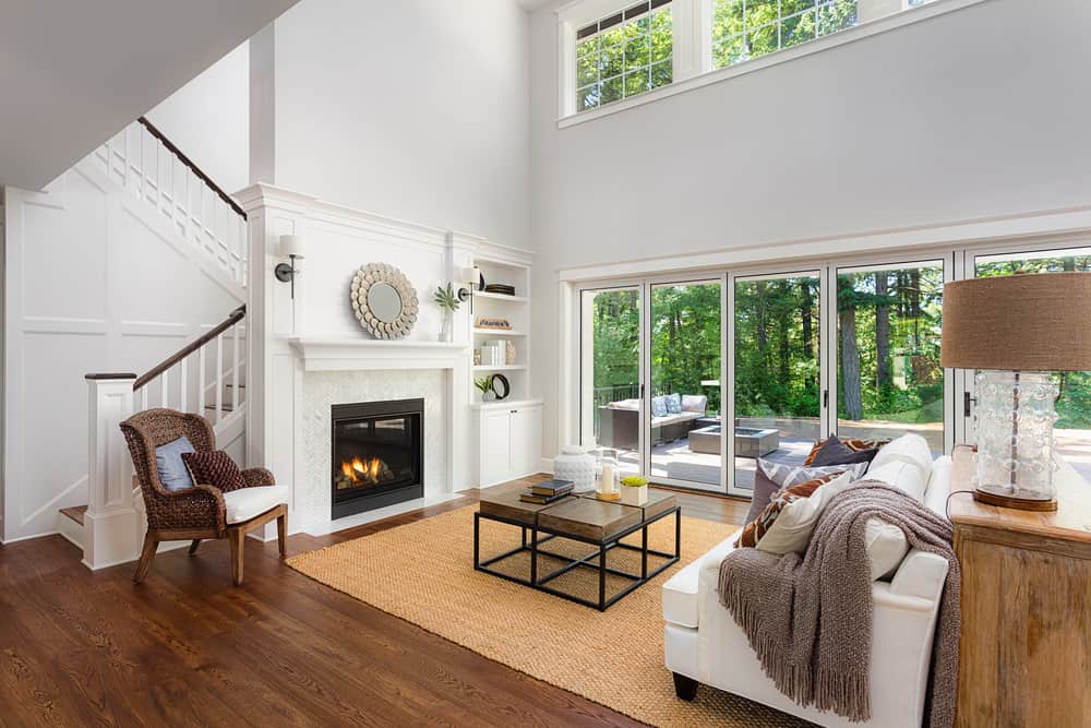 这个家拥有一个美丽的生活空间，硬木地板和一个优雅的地毯。白色沙发前面有一个壁炉。高高的天花板给这个家增添了优雅。