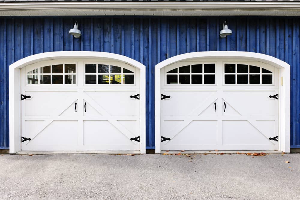 引人注目的白色马车风格的车库门在蓝色的家。