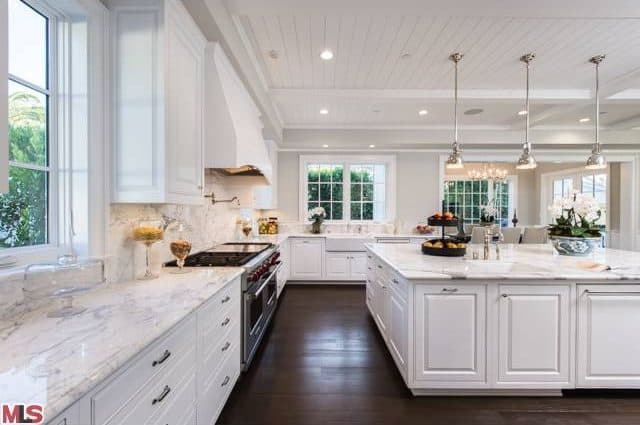 白色厨房拥有大理石台面，而吊灯和凹形灯与硬木地板很好地匹配。