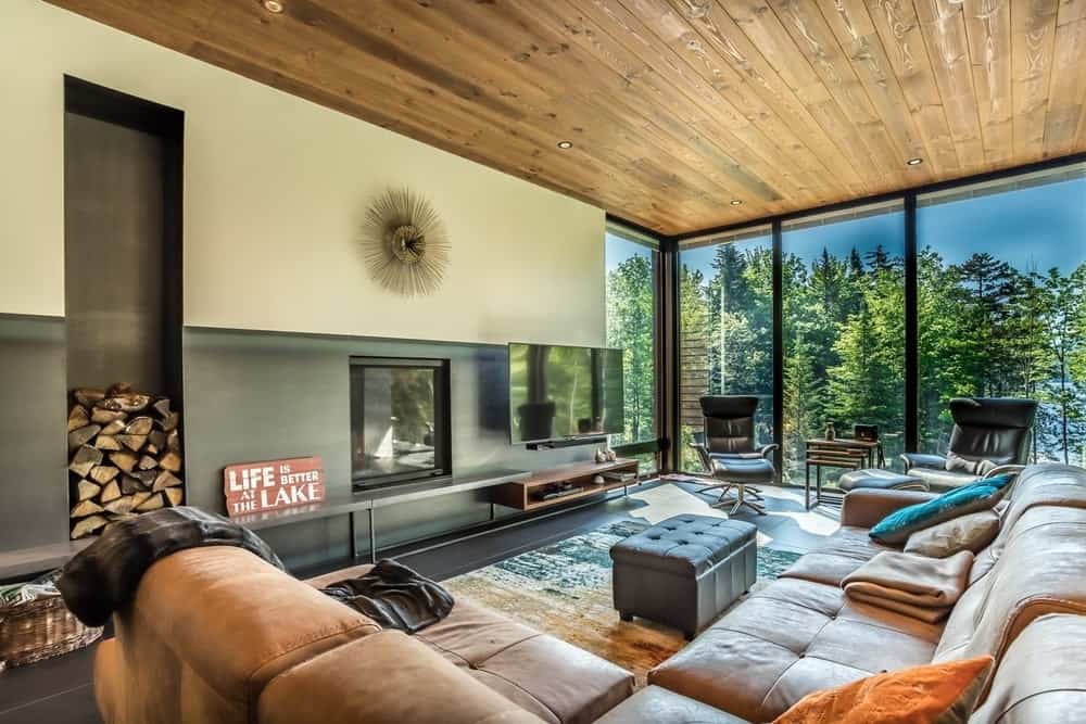 沙发套装与硬木天花板完美地融合在一起，而嵌入式灯照亮了客厅。图片来源:Dominic Boudreau