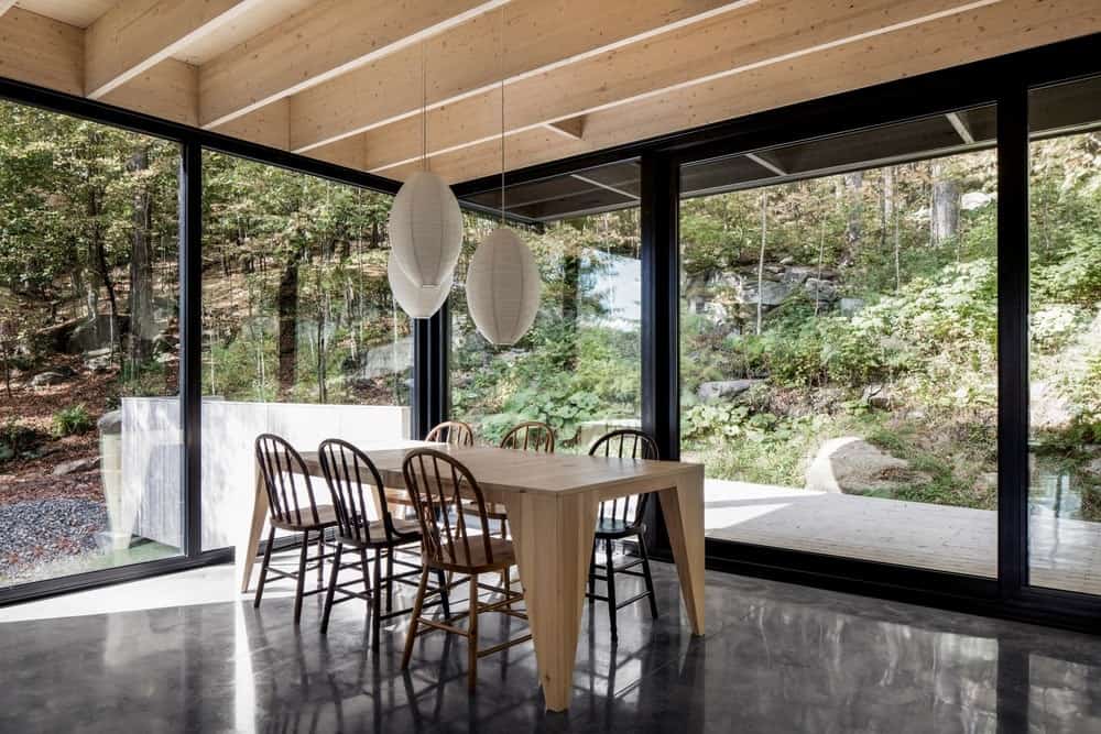 在这个全玻璃餐厅里，你可以感受到你与自然融为一体。它包括一张木桌和配套的椅子，与木梁天花板相辅相成。