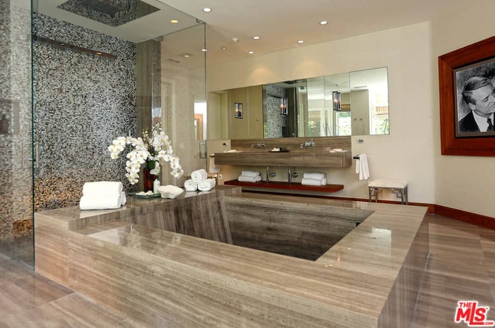 主浴室带有一个令人惊叹的大浴缸，一个时尚的步入式淋浴间和一个由嵌入式天花板灯照亮的浮动梳妆台双水槽。