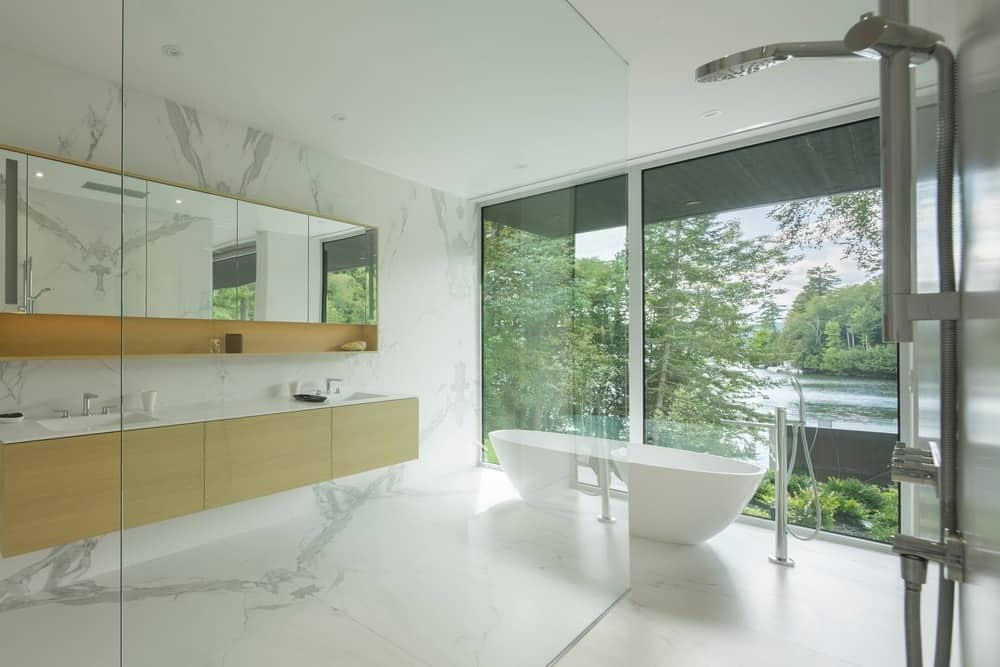主浴室设有白色大理石瓷砖地板和墙壁，以及靠近玻璃窗的独立浴缸。一个浮动的梳妆台包括两个水槽，上面有一个完整的药柜镜子。