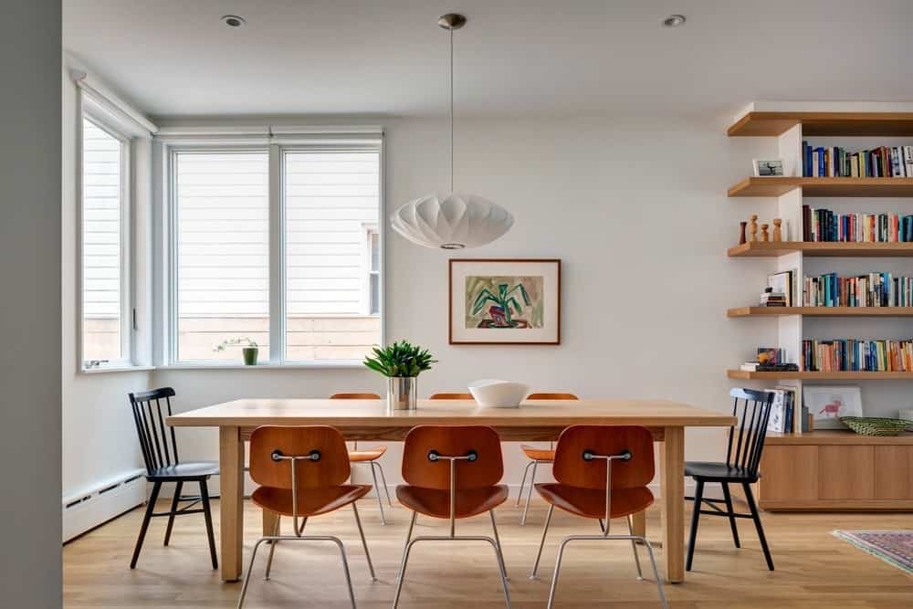 白色的餐厅空间，长方形的木制餐桌，与乙烯基地板上不匹配的椅子搭配。