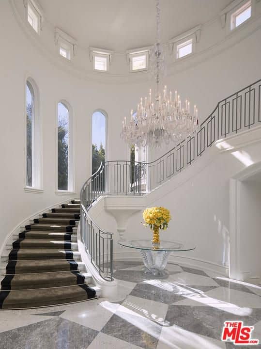 巨大的白色门厅设有一个奇妙的楼梯，由令人惊叹的大吊灯照亮。