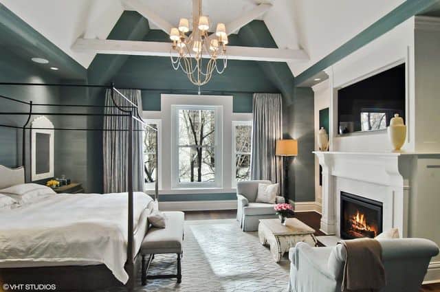 华丽的主卧室拥有一张金属顶棚床和一个可爱的吊灯，挂在白色木梁框架的拱形天花板上。