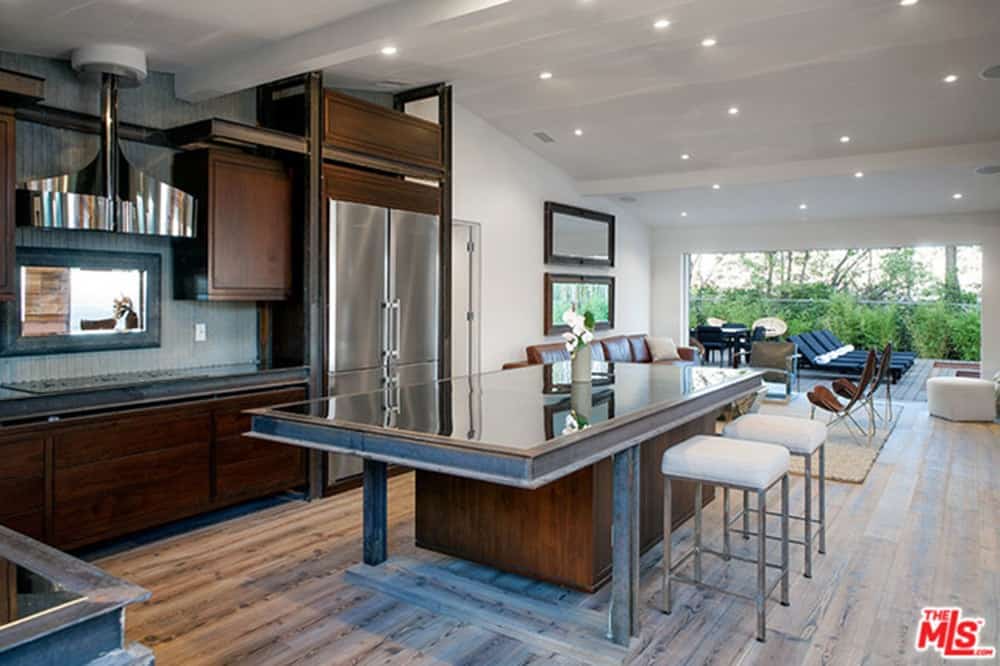 这个现代厨房提供了一个坚固的玻璃台面和一个空间的早餐吧。硬木地板与厨房的其他细节(如棕色橱柜)搭配起来很好看。