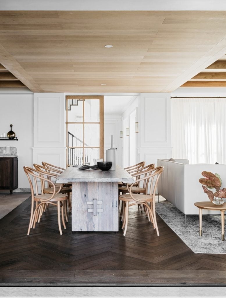 小屋风格的餐厅，木质天花板和人字纹硬木地板。它的特色是一个质朴的餐桌和圆形藤椅。