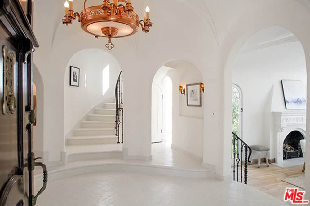白色门厅设有楼梯上的铁栏杆和白色墙壁上的墙壁照明。