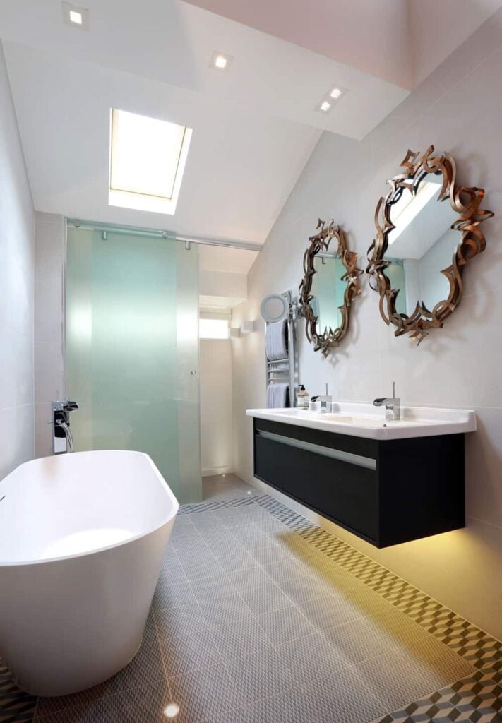 当代风格的主浴室，配有一对优雅的镜子，时尚的浮动梳妆台上有一个双水槽，一个独立的浴缸和一个步入式淋浴间。