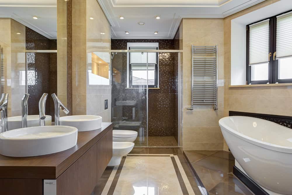 现代米色和深棕色浴室，带两个水槽和独立式浴缸。