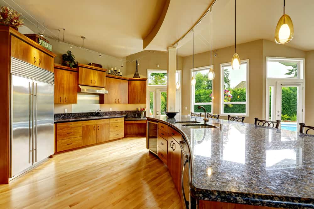 一个有乡村细节的大厨房拥有一个大厨房岛，花岗岩台面由四盏美丽的吊灯照亮。