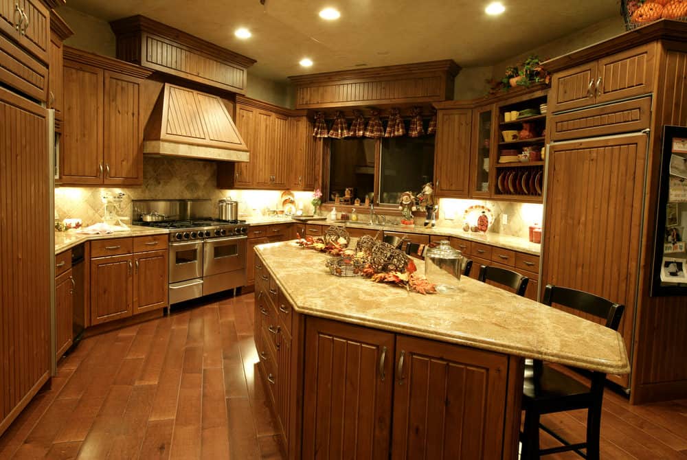 胡桃木完成的厨房有一个弧形的中央岛，设有大理石台面。灯光与厨房的风格很相配。