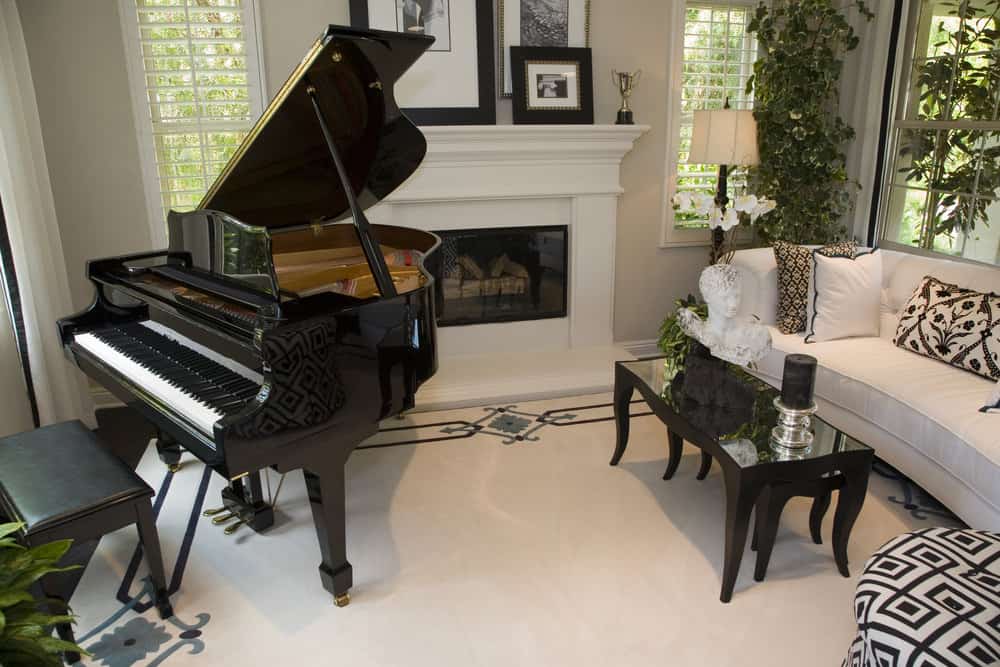 舒适的客厅，白色地板，白色壁炉和黑色婴儿三角钢琴。