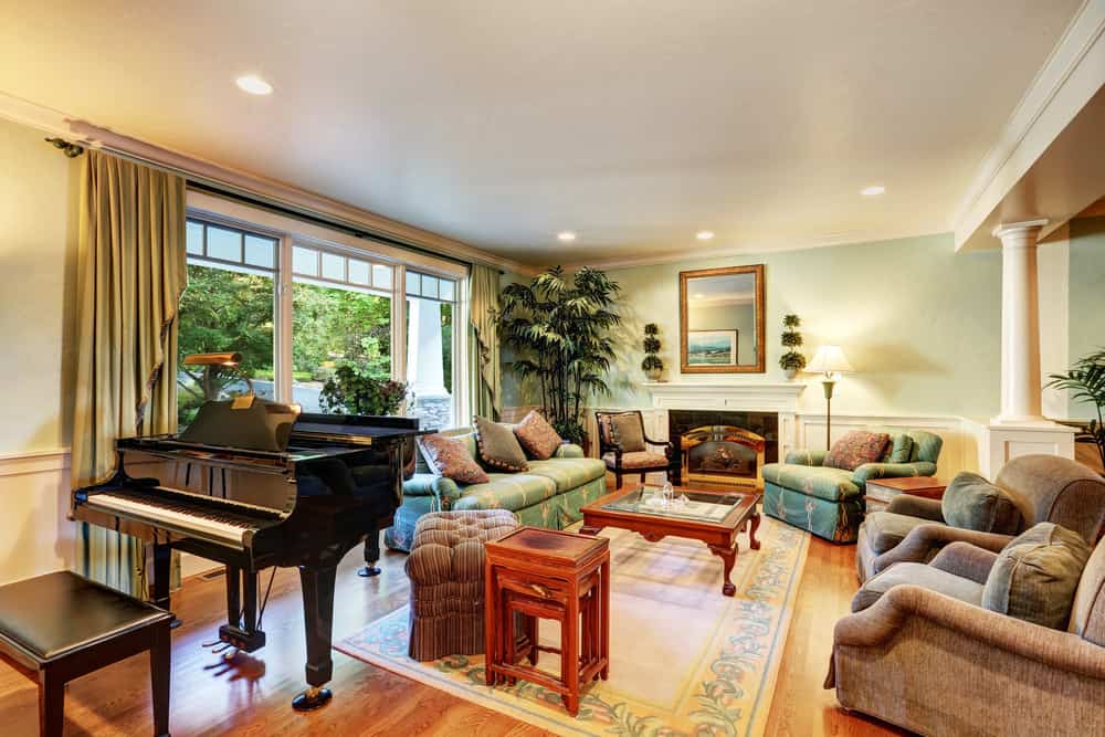 这个正式的客厅拥有时尚的座椅和时尚的壁炉，以及覆盖硬木地板的可爱地毯。还有一架钢琴看起来也很高档。