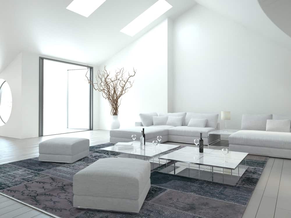 白色的客厅里铺着灰色的硬木地板，上面铺着灰色的地毯。房间提供了一组白色座椅和一对玻璃顶部中心桌。