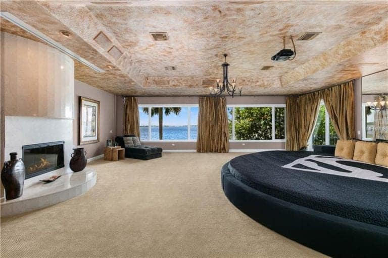 豪华的主卧室配有藏青色圆床和带平台的现代壁炉。它有玻璃窗，可以看到美丽的海滩全景。