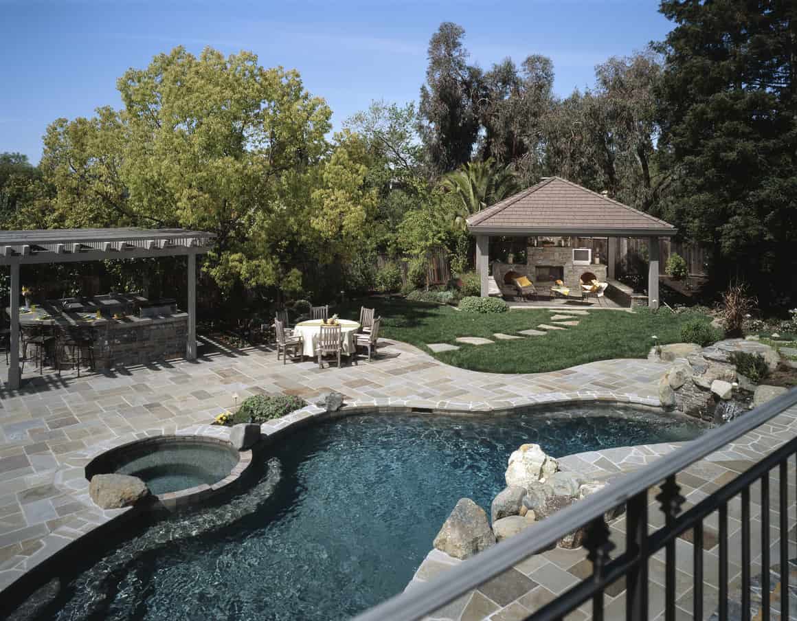 华丽的自由形式游泳池与灰色的石头露台在可爱的后院。