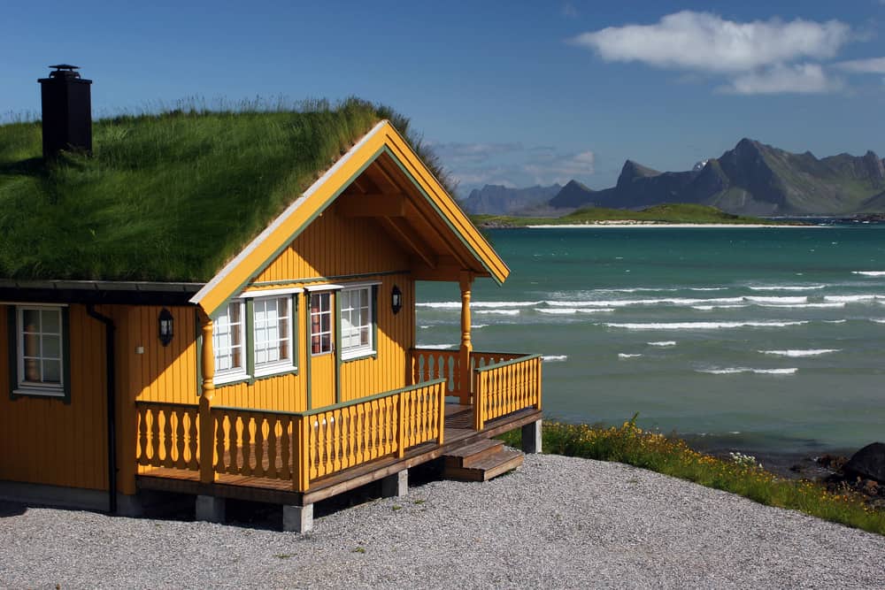 橙黄色的海滩小屋，屋顶是草，前甲板位于斯堪的纳维亚半岛的海滩上。