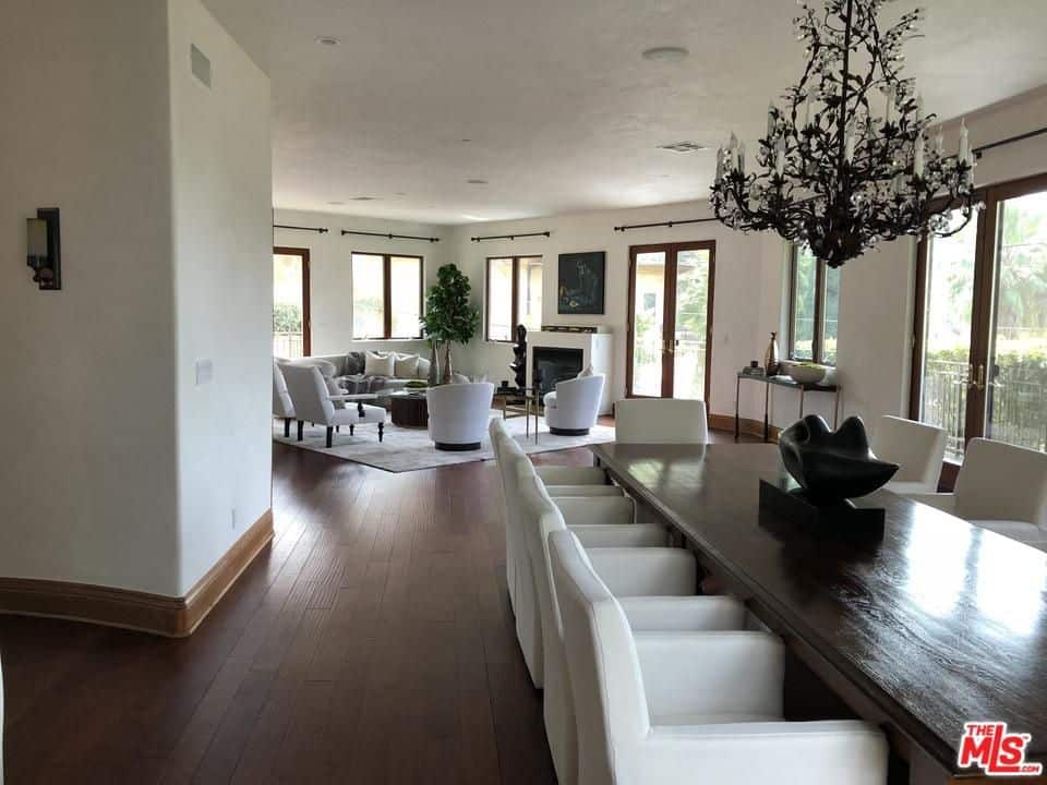 白色软垫椅子与华丽的枝形吊灯和与硬木地板融为一体的深色木质餐桌形成鲜明对比。这个开放式用餐区与客厅共用一个空间。