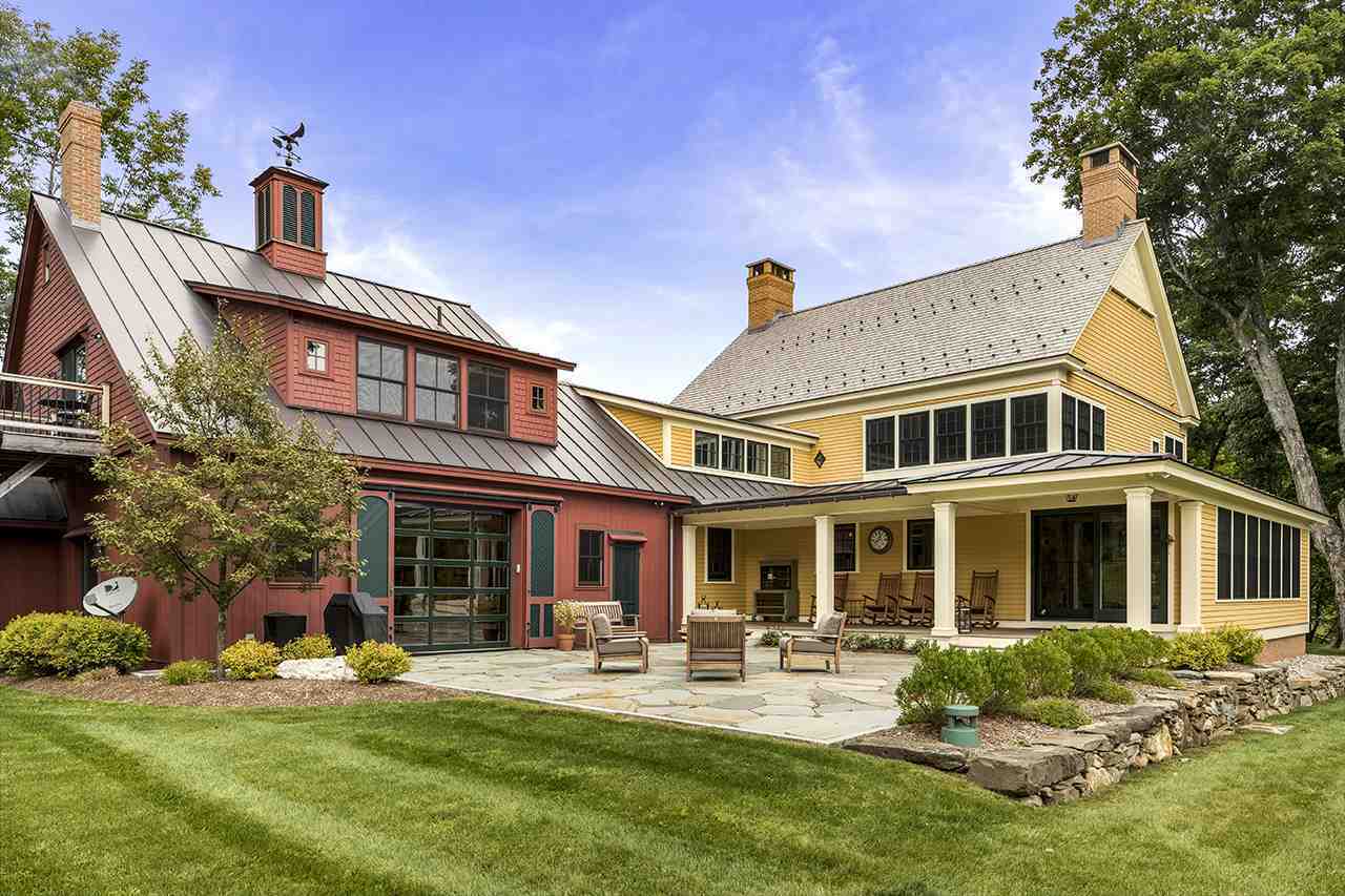 一个质朴的黄色乡村房子，拥有一个放松的庭院和花园区域，广阔的维护良好的草坪。