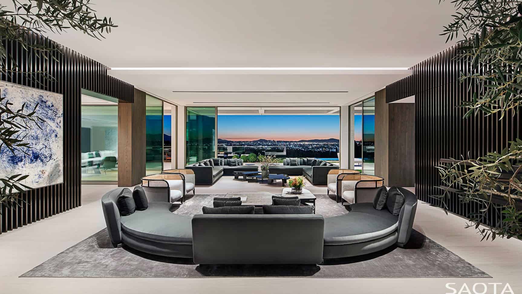 正式的客厅拥有现代舒适的沙发，以及室内植物和玻璃墙。图片来源:Adam Letch