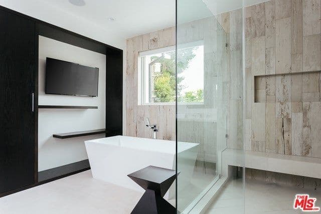 一间Modish的主要浴室，在墙上提供宽屏电视，同时浸入独立式浴缸中。也有开放式淋浴。